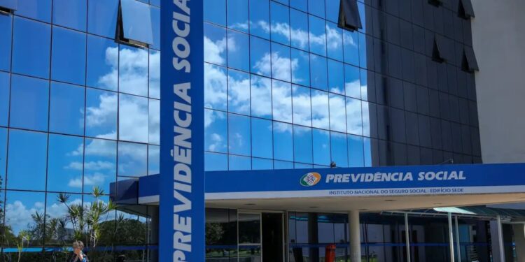 Fachada espelhada do prédio da Previdência Social do INSS em dia ensolarado.