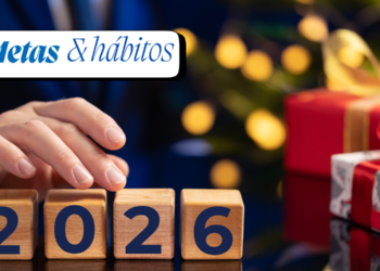 Mão ajustando blocos de madeira com números 2026 ao lado de presentes festivos.