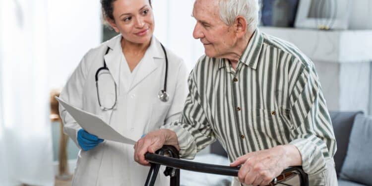 Médica avaliando paciente idoso com andador durante atendimento relacionado ao mutirão de perícias do INSS.