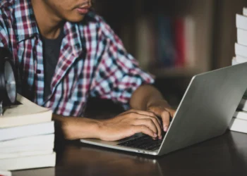 Estudante utilizando notebook para acompanhar edital de oportunidade para nível médio da Prefeitura.