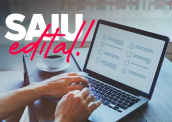 Pessoa digitando em notebook com checklist na tela e xícara de café ao lado em mesa de madeira