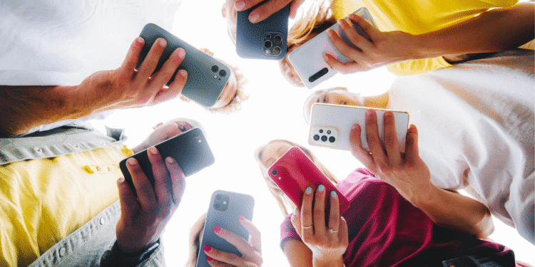 Pessoas formando círculo segurando diferentes smartphones modernos em várias cores.