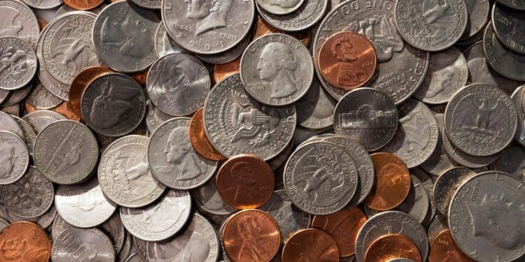 Visão aérea de diversas moedas americanas antigas e modernas misturadas, incluindo moedas de Kennedy, Washington e Lincoln, ilustrando a conservação de moedas raras.