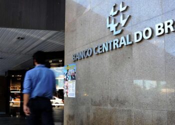 Fachada do Banco Central do Brasil com homem de camisa azul caminhando em frente ao prédio