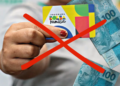 Cartão do Bolsa Família com dinheiro sendo barrado, representando cancelamentos após novo sistema de desligamento em cinco meses