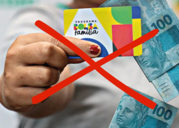 Cartão do Bolsa Família com dinheiro sendo barrado, representando cancelamentos após novo sistema de desligamento em cinco meses