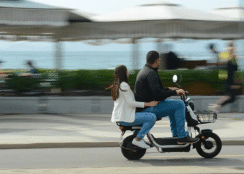 Homem e mulher andando juntos em moto elétrica próximo ao mar com sensação de movimento