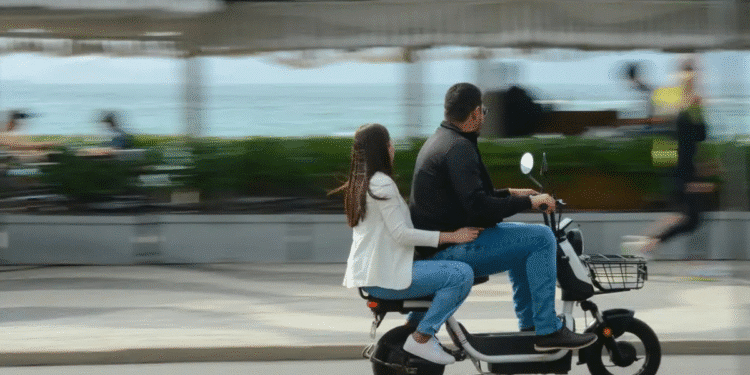 Homem e mulher andando juntos em moto elétrica próximo ao mar com sensação de movimento
