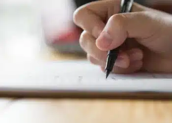 Pessoa preenchendo um formulário, ilustrando orientações para conferir o local da prova discursiva do CNU 2025.