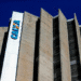 Fachada moderna do edifício da Caixa Econômica Federal com estrutura de concreto e logotipo azul contra céu azul