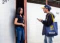 Recenseador do IBGE conversando com moradora na porta de sua casa durante coleta de dados do Censo 2020.
