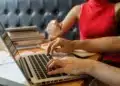 Duas pessoas trabalhando em laptop e anotações durante preparação para concursos públicos.