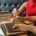 Duas pessoas trabalhando em laptop e anotações durante preparação para concursos públicos.