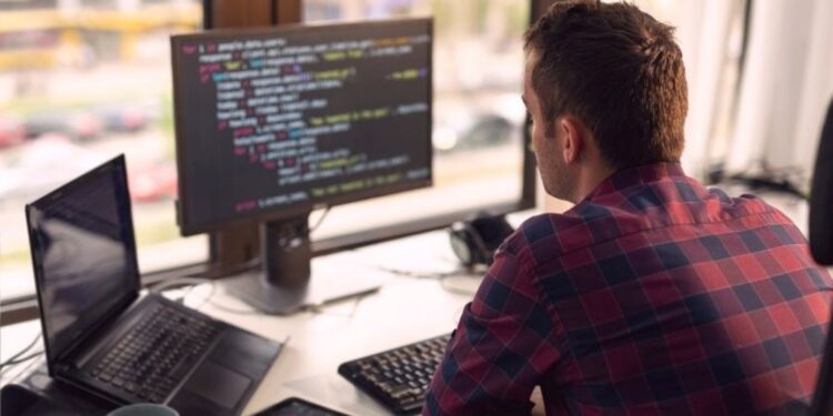 Profissional de tecnologia trabalhando em escritório moderno, representando as profissões em alta para 2026.