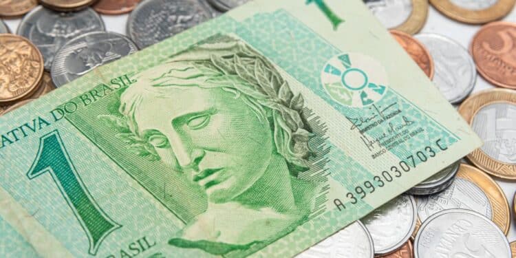 Cédula antiga de 1 Real sobre diversas moedas brasileiras. A imagem simboliza a busca por dinheiro raro da primeira família do Real, que pode valer até R$ 2.300.