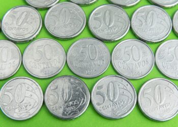 Visão aproximada de uma moeda de 50 centavos de 2019 segurada por dedos, destacando a letra "A" próxima à data.