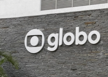 Logo branco da emissora Globo fixado em parede de pedra cinza