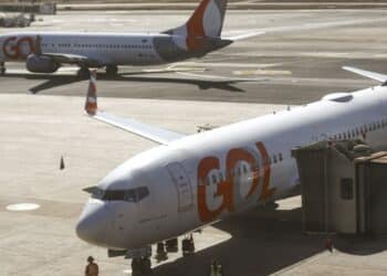 Avião da companhia aérea GOL na ponte de embarque no aeroporto com equipe de solo