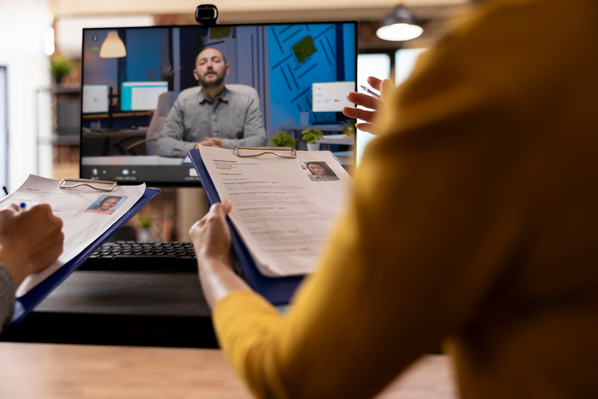 Entrevista de emprego Pessoas avaliando currículos durante entrevista de emprego pela internet com candidato na tela do computador