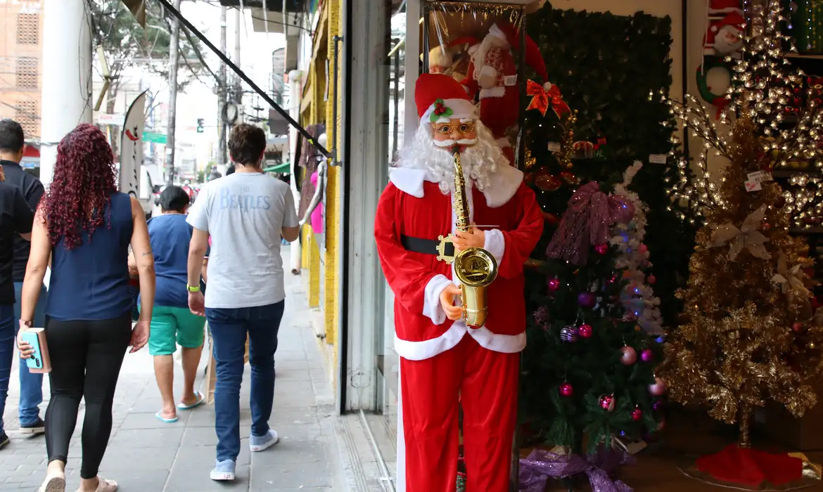 Decoração de Natal em loja com Papai Noel tocando saxofone em área comercial movimentada