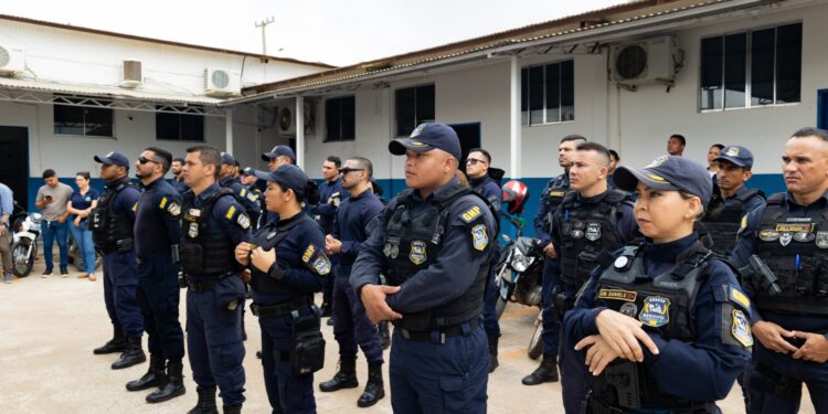 Grupo de guardas municipais em uniformes azuis durante formação ao ar livre em área institucional.