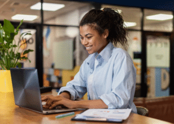 Mulher digitando em notebook enquanto trabalha remotamente em um ambiente moderno.