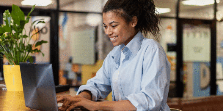 Mulher digitando em notebook enquanto trabalha remotamente em um ambiente moderno.