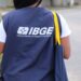 Pessoa vestindo colete azul do IBGE em rua analisando dados para pesquisa do Instituto Brasileiro de Geografia e Estatística