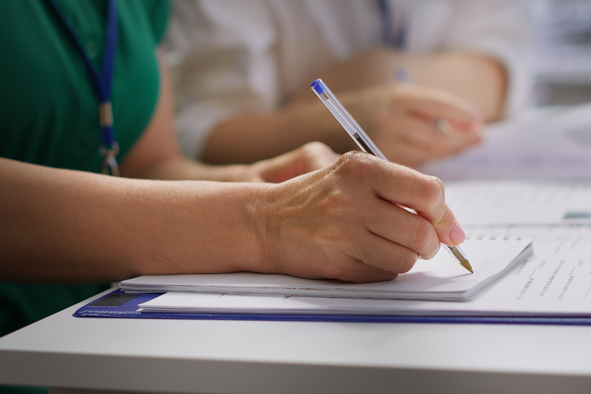 Inscrição Emprego Mão de pessoa escrevendo em caderno branco com caneta azul sobre mesa com documentos