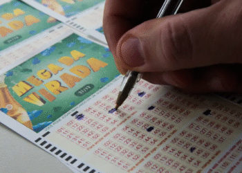 Pessoa marcando números no bilhete da Mega Virada com uma caneta azul.
