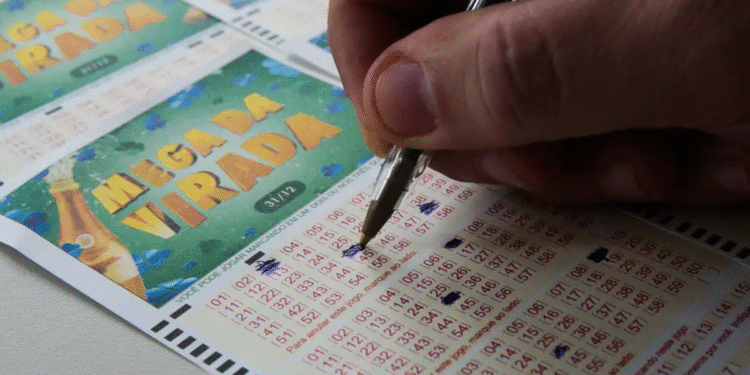 Pessoa marcando números no bilhete da Mega Virada com uma caneta azul.