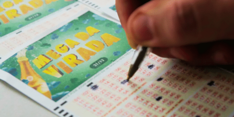 Mão preenchendo volante da Mega da Virada com caneta em bilhete de loteria oficial