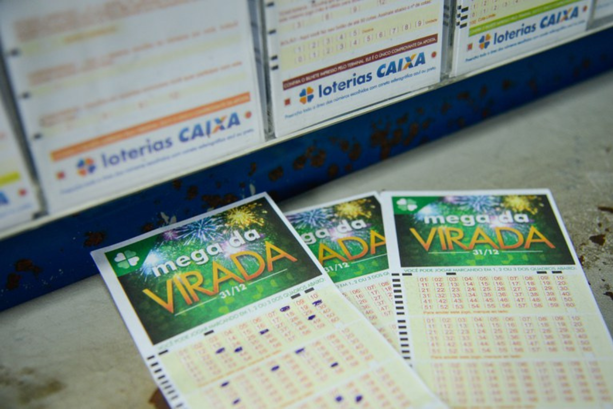 Três volantes da Mega da Virada da Loteria Caixa sobre mesa com números marcados