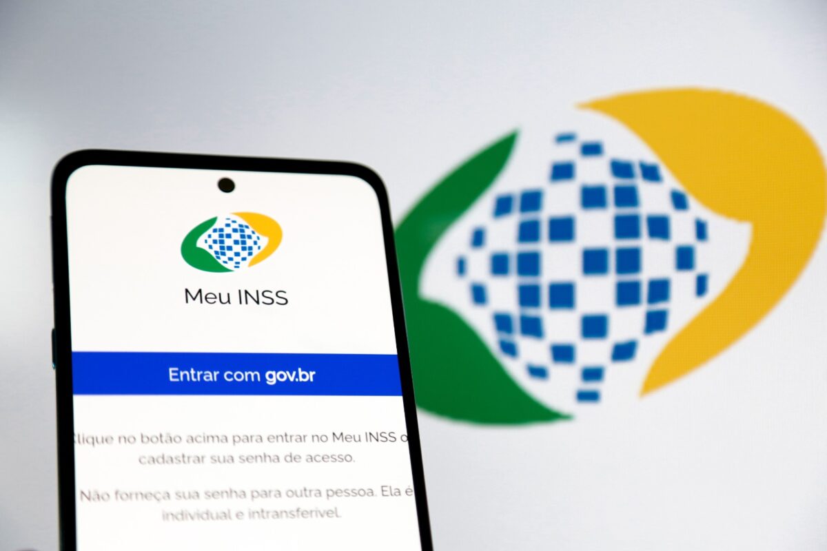 Meu INSS Tela de smartphone com login do aplicativo Meu INSS para entrar com conta gov.br em fundo branco com logo do INSS desfocado