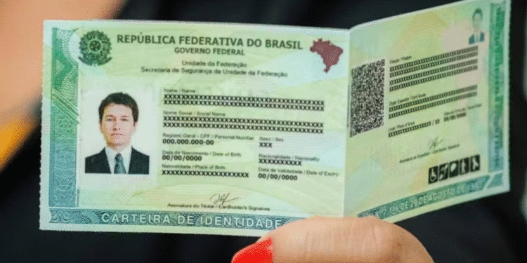 Mão feminina segurando carteira de identidade brasileira aberta com dados pessoais censurados