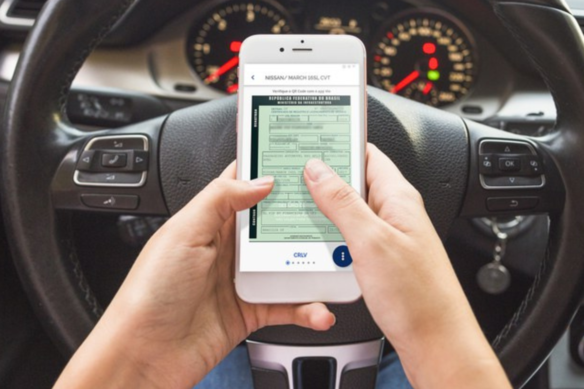 Pagamento IPVA Pessoa segurando celular com documento do carro digital na tela dentro de um carro