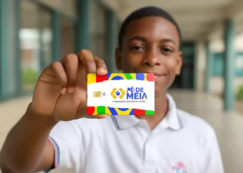 Estudante segurando cartão do programa Pé-de-Meia em frente à escola representando os pagamentos liberados pelo MEC.