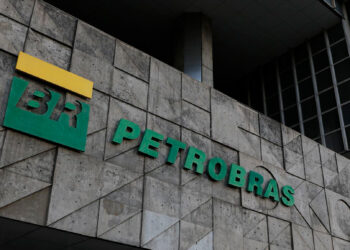 Fachada de prédio com logo da Petrobras em letras verdes e amarelo sobre parede de concreto