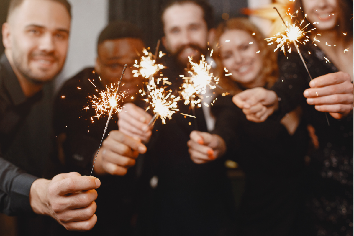 Pessoas sorrindo segurando velas de festa acesas em ambiente festivo