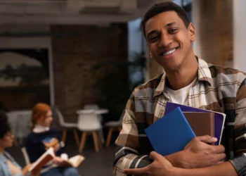 Estudante sorridente segurando livros, refletindo sobre sua futura profissão.
