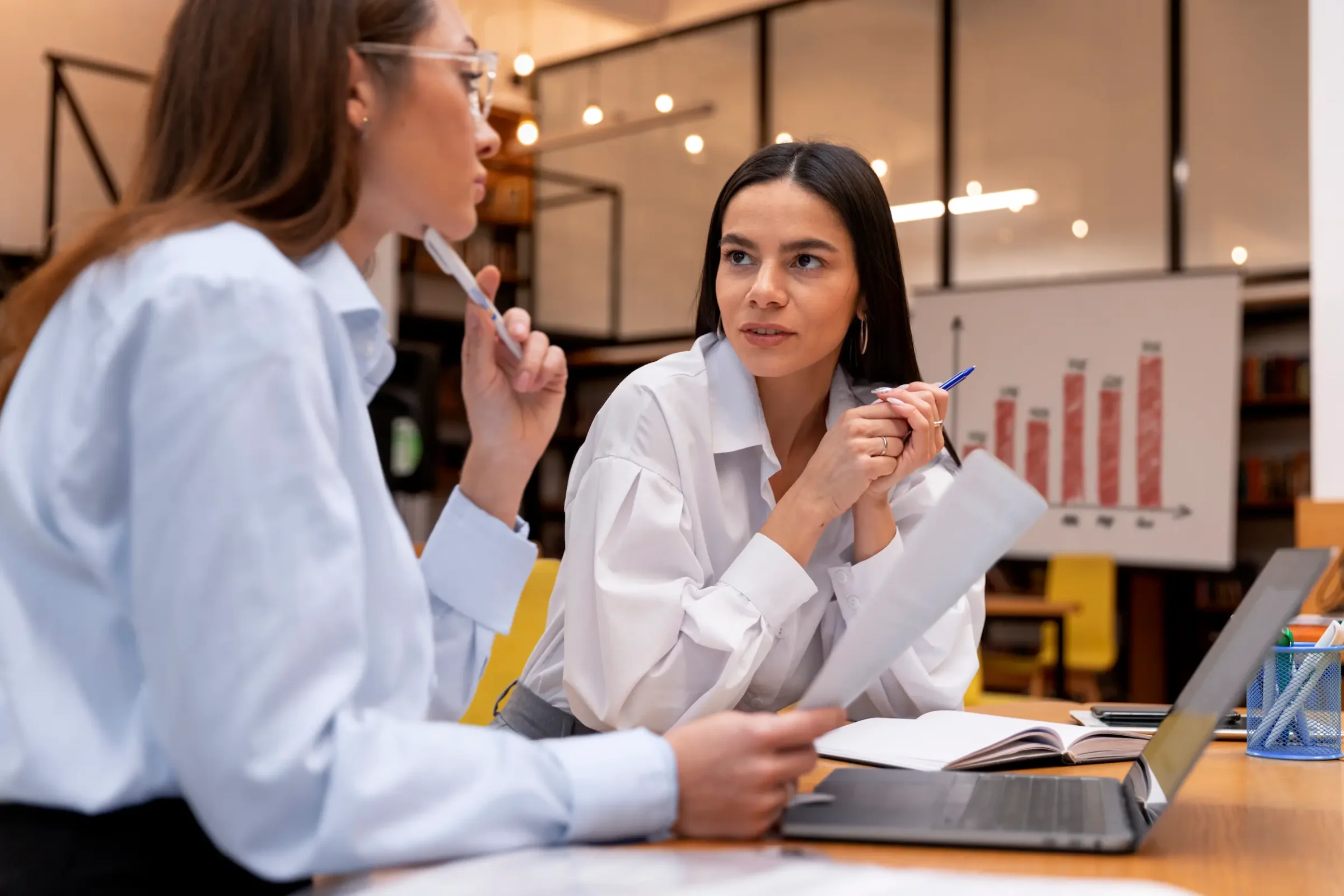 Profissionais discutindo estratégias e analisando gráficos, destacando as habilidades analíticas e adaptabilidade valorizadas no mercado de trabalho em 2026.