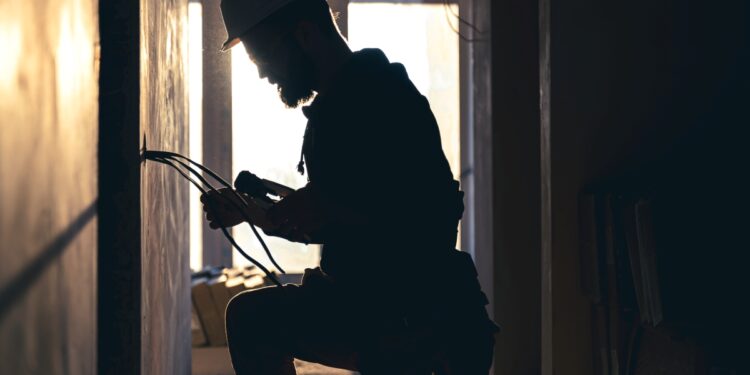 Profissional de construção civil realizando trabalho elétrico, com foco em habilidades demandadas no mercado.