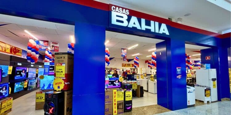 Entrada da loja Casas Bahia com colunas em azul e displays de eletrônicos com etiquetas de oferta