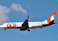Avião comercial da Gol Linhas Aéreas com logo laranja e branco voando sob céu azul com poucas nuvens