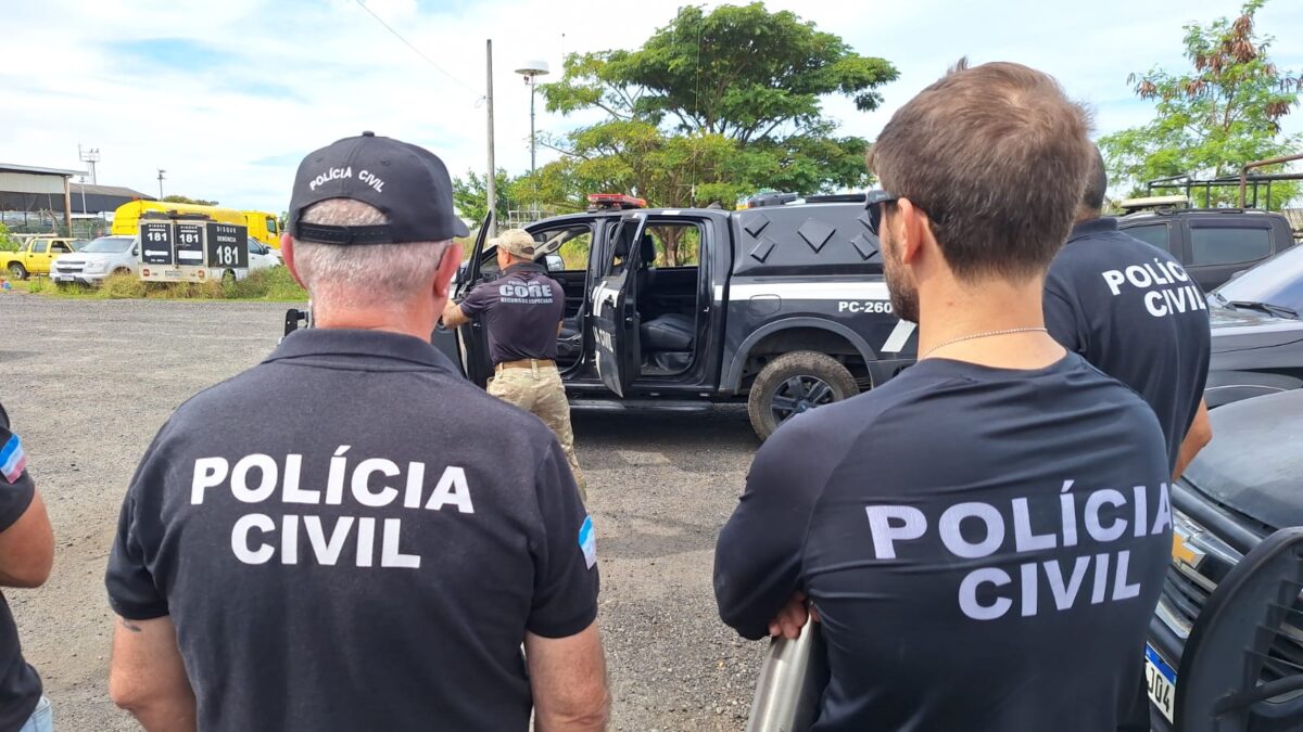 Agentes da Polícia Civil e CORE junto a viatura preta em área aberta durante operação policial