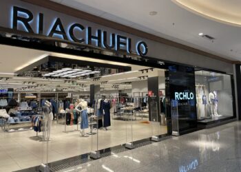 Entrada da loja Riachuelo em shopping com manequins exibindo roupas e iluminação interna