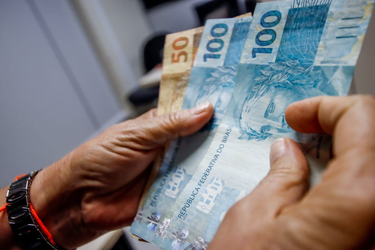 13º salário do INSS em 2026 Pessoa segurando notas de 50 e 100 reais, dinheiro em espécie brasileiro