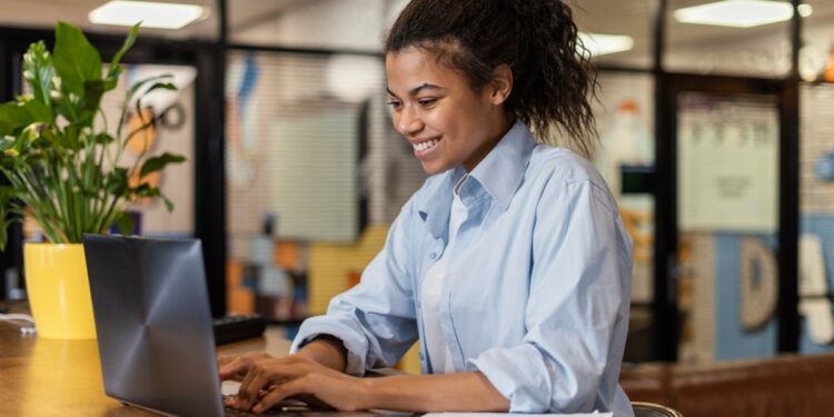 Estudante em ambiente corporativo utilizando notebook em programa de estágio no estado de São Paulo