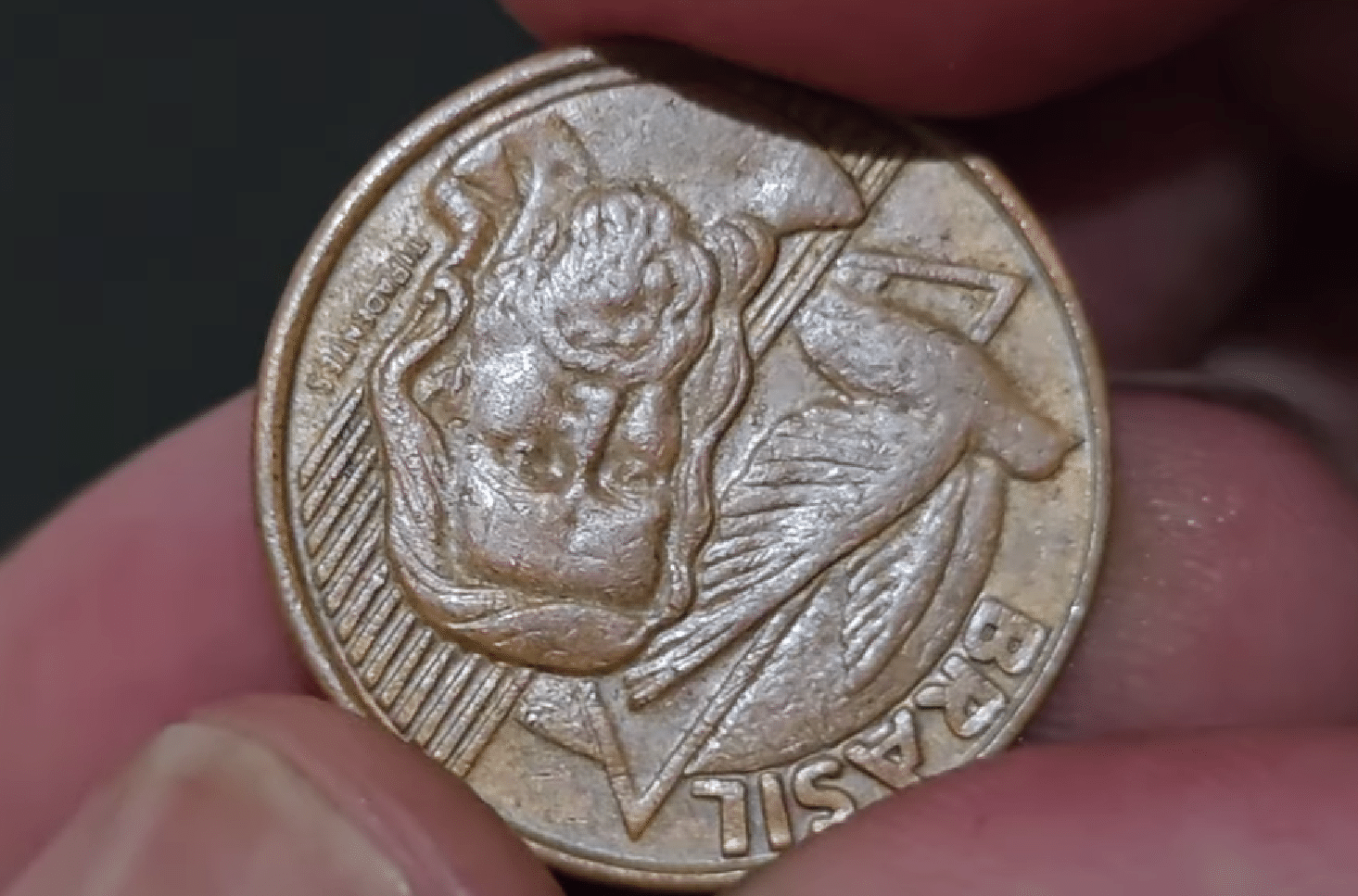 Close do reverso de uma moeda de 5 centavos de 2002, exibindo a efígie de Tiradentes e o nome Brasil de cabeça para baixo, caracterizando o erro de reverso invertido.