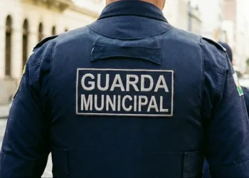 Uniforme de um Guarda Municipal com o texto 'GUARDA MUNICIPAL' visível na parte de trás da camisa, enquanto ele patrulha a cidade, representado a seleção da Prefeitura para o cargo de Guarda Municipal.